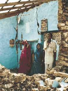  Indira Jhala stands with her family in what remains of their home 