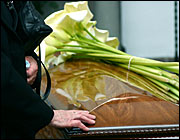 hand and flowers on coffin (Dariusz Buczynski/iStockphoto)
