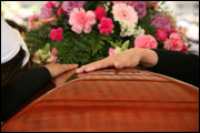 Hand on casket at funeral (Nick M. Do/iStockphoto)